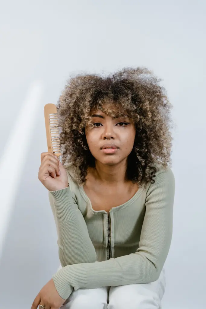 Femme aux cheveux texturés tenant un peigne en bois à dents larges
